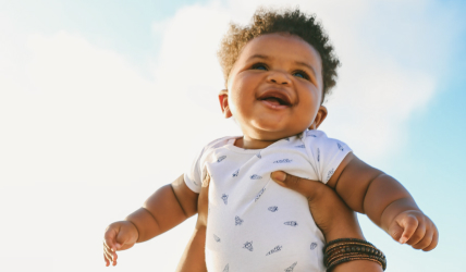 A father holding up a smiling baby.